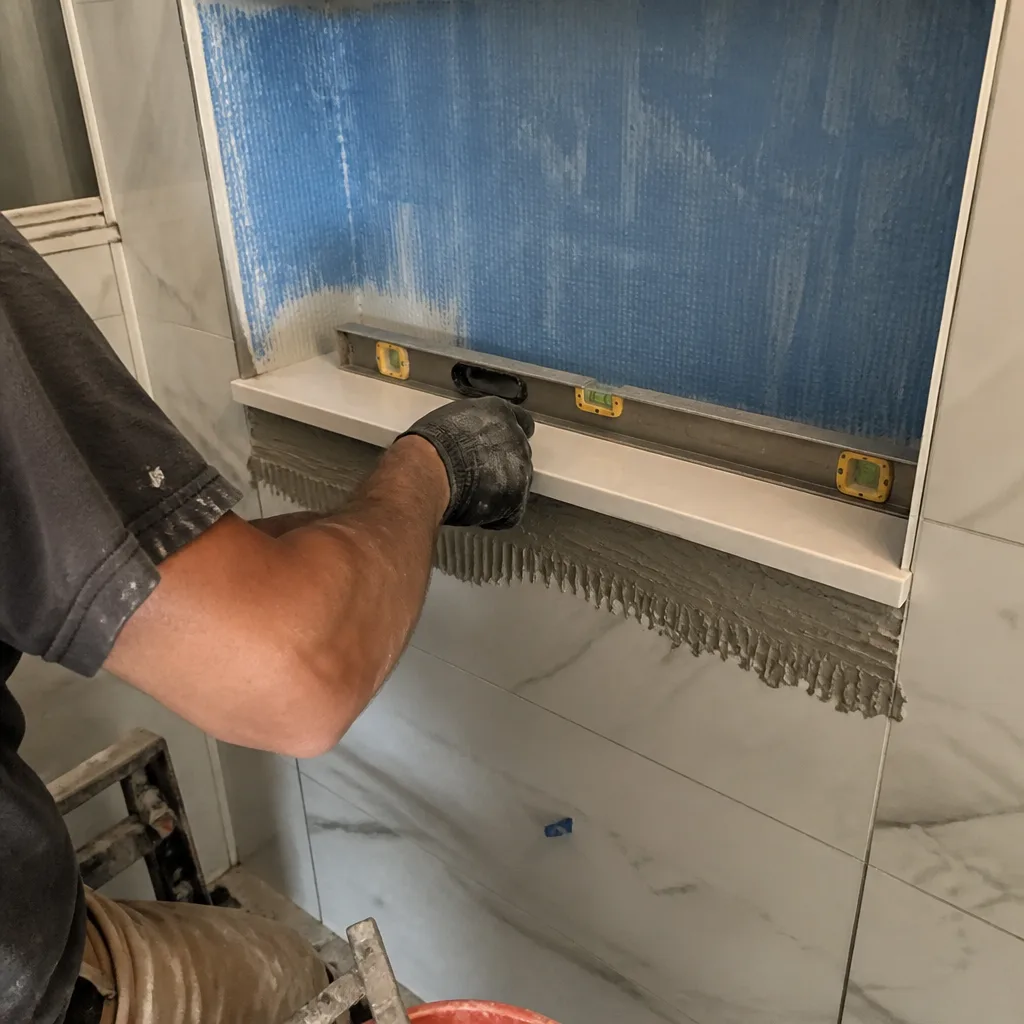 Professional contractor leveling a shelf during a custom bathroom remodeling project